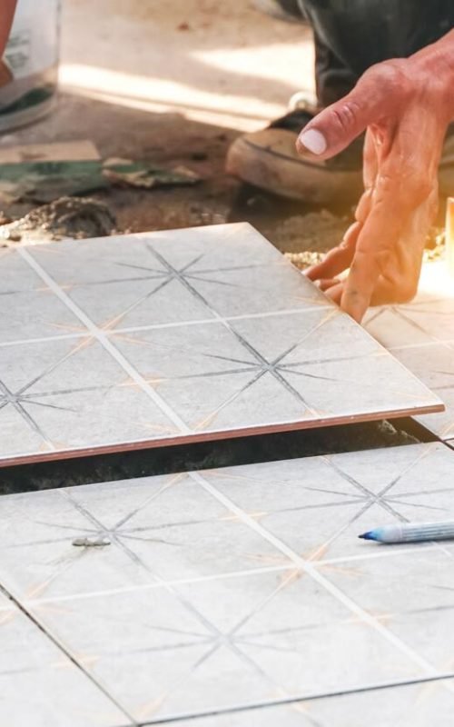 Worker,Placing,Ceramic,Floor,Tiles,On,A,Surface,With,Adhesive